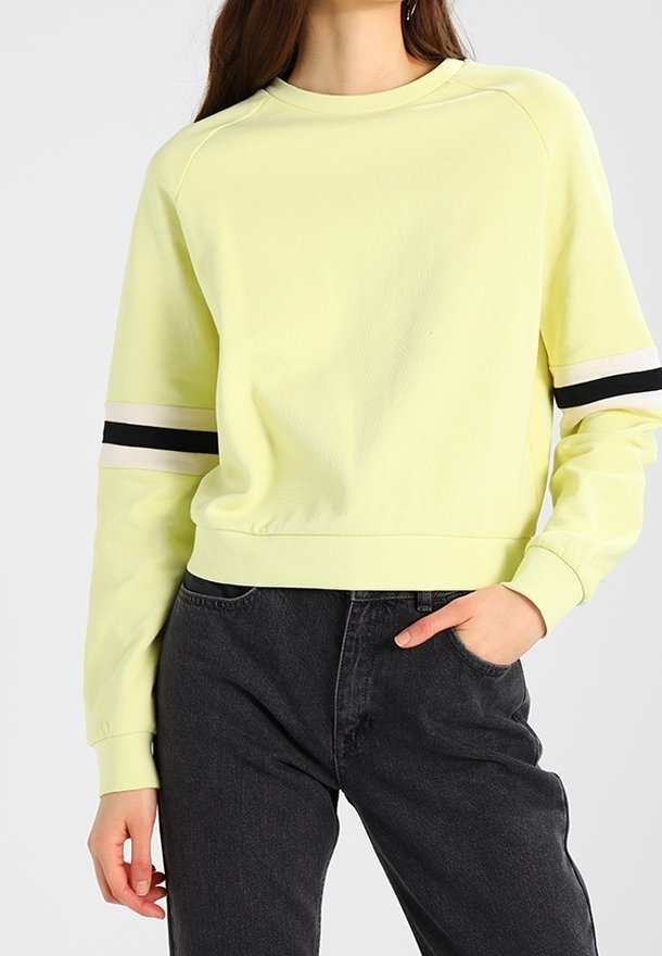 Light yellow sweatshirt with a crew neckline and raglan sleeves, featuring black and white stripes on the sleeves and a relaxed fit.