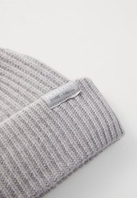 Grijze gebreide beanie met een geribbelde textuur, voorzien van een klein grijs label met "JACK&JONES STUDIO Collection" dat op de boord is gestikt.