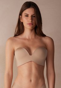 Beige strapless bh met gladde cups, een sweetheart halslijn en naadloos ontwerp. Gemaakt van een zachte, rekbare stof voor comfort.