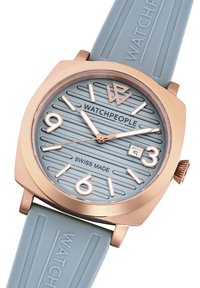 Astoņstūraina pulksteņa rožu zelta korpuss, gaiši zila teksturēta skala, reljefa stundu marķieri un gaiši zila gumijas siksna ar zīmolu.