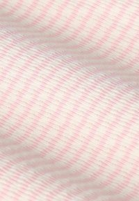 Tissu en coton présentant une texture douce avec des rayures alternées rose clair et blanches, créant un motif subtil sur le matériau.