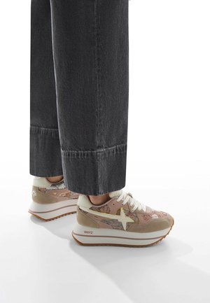 Sneakers feature a light pink mesh upper with beige suede accents and a white lacing system. Thick white soles with a textured brown outsole.