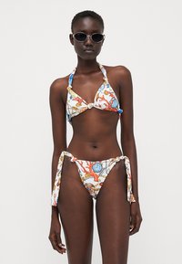 Set de bikini format dintr-un sutien triunghiular și chiloți cu legare laterală, realizat dintr-un material cu modele colorate de corali și scoici pe un fundal alb.