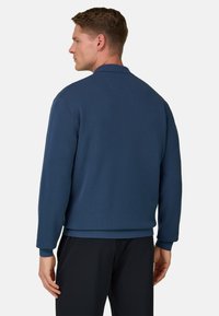 Mørkeblå pullover-sweatshirt med lange ærmer, krave og løs pasform, lavet af blødt tekstureret stof.