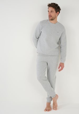 Grijze sweatshirt- en broekset met wafelstructuur. Voorzien van ribbelmanchetten en een ronde halslijn. De stof lijkt zacht en ademend te zijn.