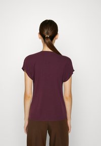 Bordeaux farvet t-shirt med kort ærme, afslappet pasform, glat tekstur, rund halsudskæring og oprullede ærmer, set bagfra.