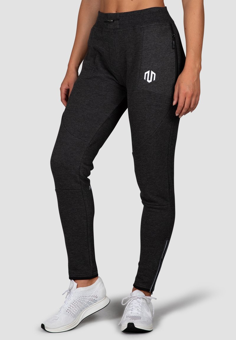 Dark gray athletic pants with a fitted design, featuring a white logo, side zip pockets, and tapered ankles. Smooth texture with stretch.