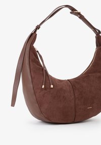 Borsa a tracolla in suede marrone e pelle texturizzata con forma curva, chiusura con zip e tracolla regolabile. Dettagliata con accenti in metallo dorato.