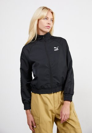Veste noire zippée en matériau léger avec un col montant, des poignets et une taille côtelés ; présente un logo Puma blanc sur la poitrine.