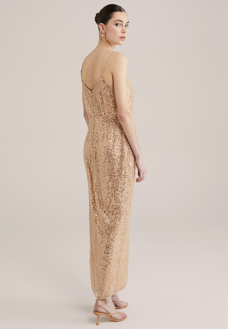 Jumpsuit w kolorze bladozłotym z cekinami, z cienkimi ramiączkami i dopasowanym topem, tworzącym smukłą sylwetkę. Gładka tekstura z połyskującymi akcentami.