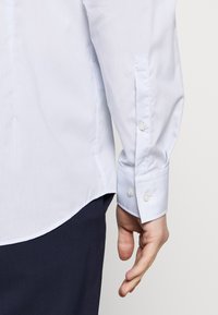 Lichtblauw gestreept overhemden van katoenmix, lange mouwen met knoopmanchetten, ronde zoom, subtiele textuur en witte knopen.