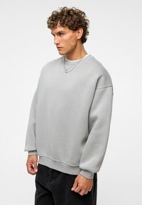 Grijze sweatshirt van zachte stof, met een ronde hals, geribbelde manchetten en een relaxte fit. Draagt comfortabel over zwarte broeken, casual ontwerp benadrukt.
