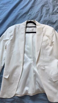 White blazer made of lightweight fabric, featuring a notched lapel, single-button closure, and a smooth, lined interior.
