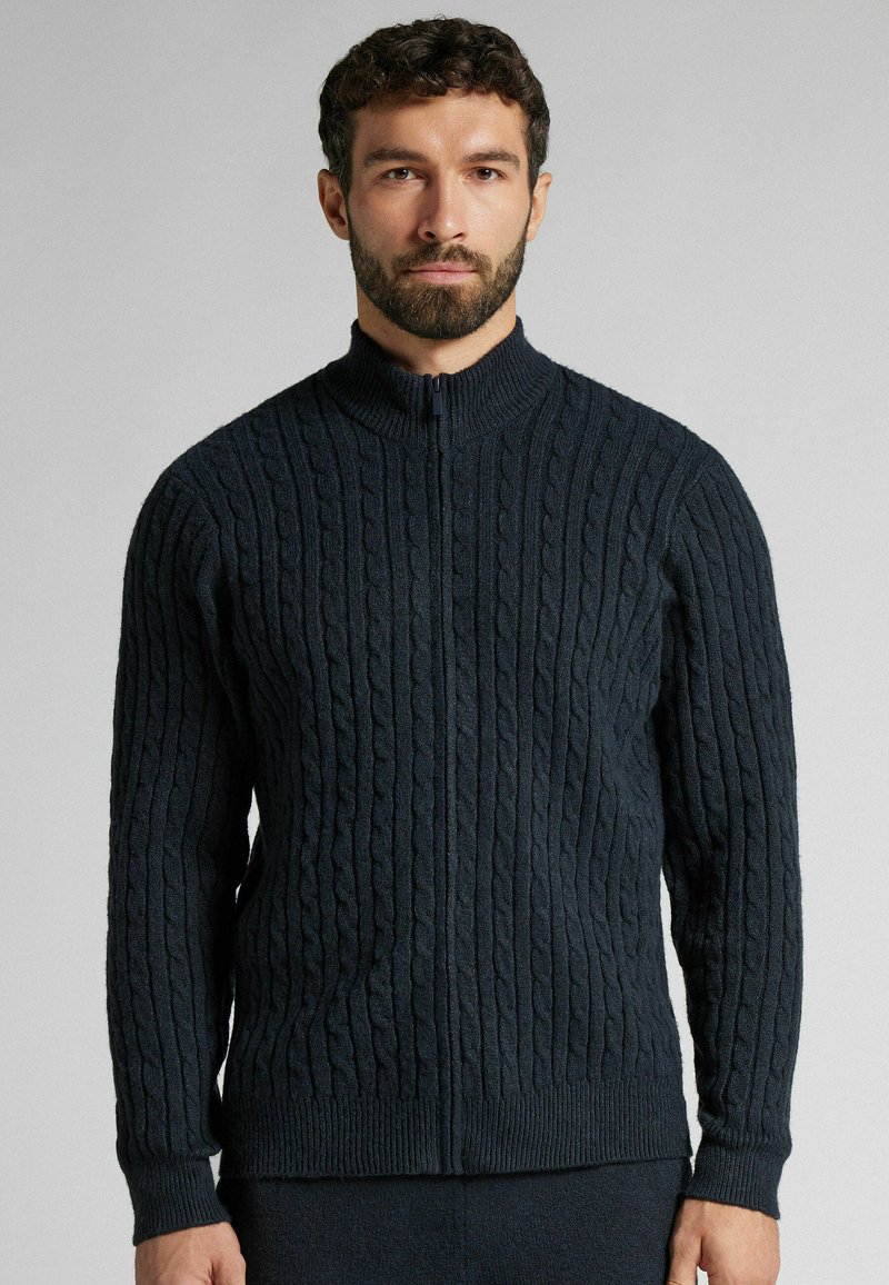 Sweat à fermeture éclair bleu marine foncé avec col côtelé et motif en maille torsadée texturée. Manches longues avec poignets ajustés et ceinture. Matière douce et confortable.