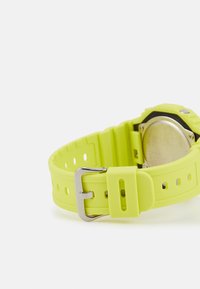 Montre en silicone jaune vif avec un bracelet texturé, dotée d'une boucle en métal et d'un boîtier rond en métal.