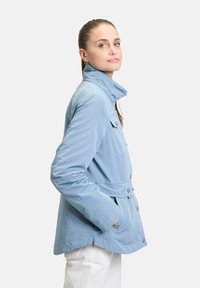 Helleblaue Softshelljacke mit hohem Kragen, Knopfverschluss, Fronttaschen und cinched Taille. Glatte Textur und lässiges Design.