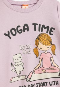 Paarse katoenen sweatshirt met de tekst "Yoga Tijd", een cartoonmeisje in een roze outfit en een kat op yogamatten, met een ontspannen uitdrukking.
