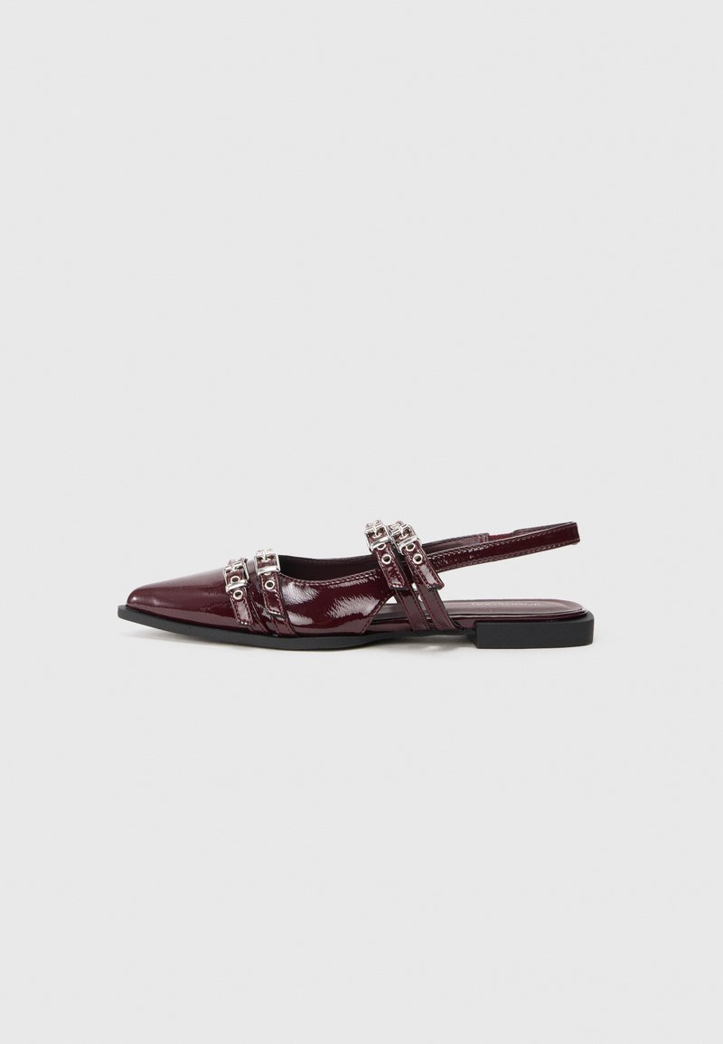 Chaussure plate slingback en cuir verni bordeaux avec un bout pointu, présentant des lanières décoratives avec des accents métalliques.