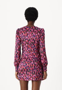 Rochie scurtă cu un model floral multicolor în nuanțe de roșu, roz și albastru; mâneci lungi cu umeri strânși; închidere cu fermoar la spate.