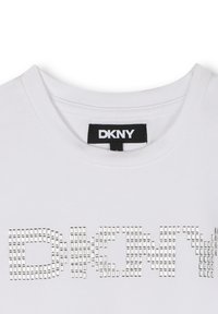Biała bawełniana koszulka z haftem, na której srebrne ćwieki ułożone są w napis "DKNY" z przodu. Klasyczny dekolt typu crew neck z gładką teksturą.