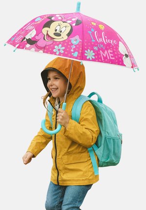 Gelbe wasserdichte Jacke, blauer Rucksack und rosa Regenschirm mit Minnie-Maus-Design. Kind mit braunen Haaren lächelt, Regentropfen sichtbar.