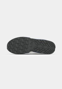 Black rubber shoe sole with a textured grip pattern, featuring a mix of solid and raised lines, and a clean design at the heel.