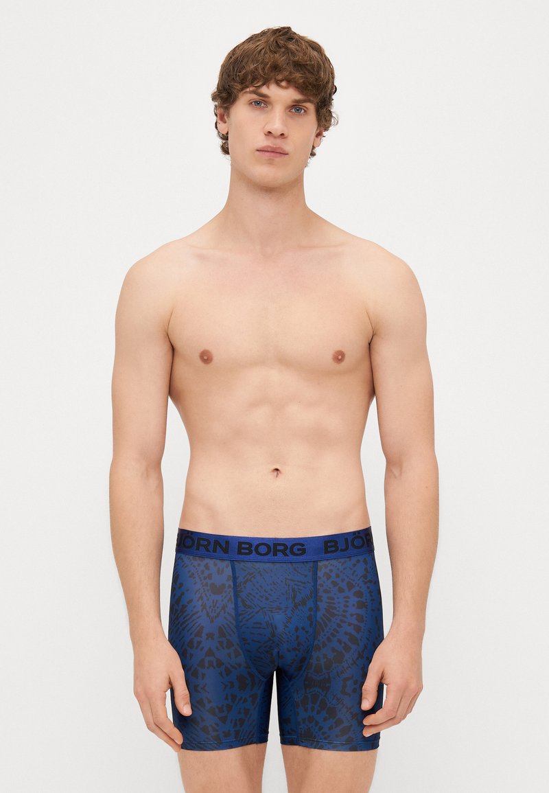 Boxer briefs azuis com um padrão abstrato preto e uma cintura azul em contraste com o texto "BJÖRN BORG." Feitos de um material macio e elástico.