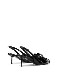 Tacchi slingback in pelle verniciata nera con punta affusolata, cinturini sottili e un dettaglio decorativo a fiocco frontale. Tacco a stiletto di 6.5 cm.