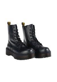 Botas negras de cuero hasta el tobillo con cordones en la parte delantera, suela de plataforma gruesa, tirador a rayas amarillas y negras, y cierre de cremallera lateral.