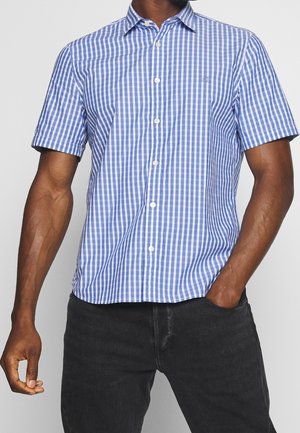 Chemise à manches courtes en vichy bleu et blanc avec un col et une fermeture à boutons, fabriquée en tissu léger, associée à un jean foncé.