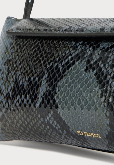 Borsa nera e blu con un motivo a scaglie, caratterizzata da una texture liscia e lucida, presenta un design in pelle di serpente e una targhetta dorata. Forma strutturata e rettangolare.