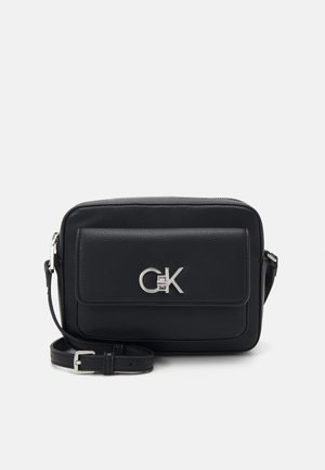 Bolso cruzado de cuero negro con cierre de cremallera, forma rectangular, bolsillo con solapa en la parte frontal y acento de logo plateado. Se incluye correa ajustable.