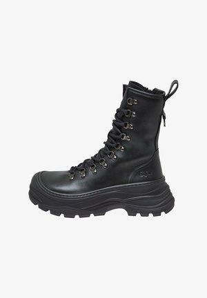 Mustad musta nahast sõjaväe saapad kõrge varrega, tekstureeritud kummitald, metallist silmad ja nöörid. Omab taga tõmbenööri mugavaks jalga panemiseks.