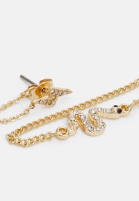 Brincos em forma de cobra em tom dourado com detalhes de strass, apresentando um design de corrente e um fecho traseiro seguro.