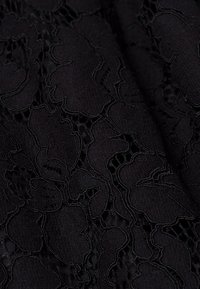 Svart spetstyg med ett blommönster som har texturerade blommor och intrikata stygn, vilket skapar en lager och detaljerad look.