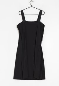 Robe noire sans manches avec larges bretelles, présentant une coupe ample et des plis sur les côtés. Fabriquée en tissu doux et lisse, suspendue à un crochet noir.