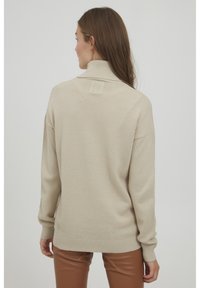 Beige Strickpullover mit hohem Kragen und strukturiertem Wabenmuster. Lange Ärmel mit gerippten Bündchen und Saum. Glatte, weiche Textur.