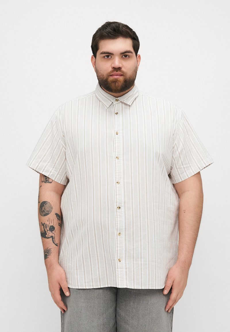 Camisa de manga corta abotonada en beige claro con rayas verticales, que presenta un collar, botones delanteros y un ajuste relajado.