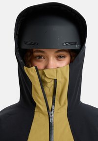 Black and gold jacket with a high collar and front zipper. Features a helmet with ventilation and a logo. Soft texture, sporty design.