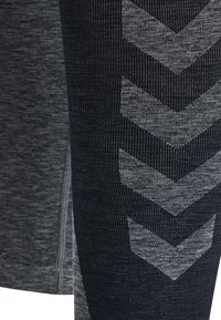 Grå träningsleggings med en strukturerad tyg. Notabla detaljer inkluderar sicksackmönster i en ljusare grå mot en mörk bakgrund.