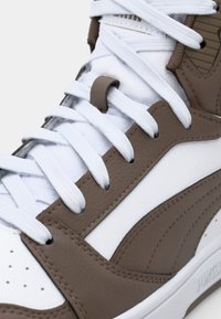 High-top sneakers with brown leather and white textile. Featuring white laces, perforated toe box, and textured side panel.