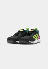 Black athletic shoes with a textured upper, featuring green and pink accents and three stripes logo. White sole with grip pattern.