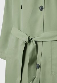 Hellgrüner Mantel mit Gürtel aus weichem Stoff, ausgestattet mit Knöpfen und einem Reverskragen, mit Taschen und glatter Textur.
