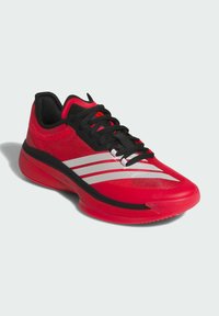 Røde atletiske sko med sorte accenter og hvide striber. Fremstillet af mesh og syntetiske materialer. Har en rund, tekstureret sål.