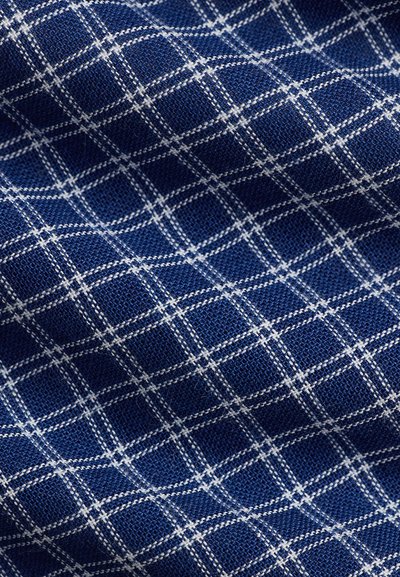 Ύφασμα σε ναυτικό μπλε με λευκό διασταυρωμένο σχέδιο πλέγματος που δημιουργεί ομοιόμορφες τετράγωνες περιοχές, εμφανίζεται σε κοντινό πλάνο με ορατή υφή και πτυχώσεις.