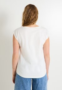 Camiseta blanca de manga corta con un corte relajado y escote redondeado, hecha de un material de algodón suave. Sin patrones ni adornos visibles.