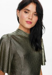 Metallic gold top featuring a high neck, textured pattern, and short sleeves. The fabric has a structured, slightly reflective quality.
