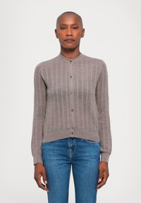 Sivý rebrovaný cardigan s okrúhlym výstrihom, zapínaním na gombíky a dlhými rukávmi. V kombinácii s modrými rifľami, obsahuje textúrovaný úpletový dizajn.