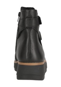 Bottine en cuir noir avec une finition texturée, dotée d'une fermeture éclair sur le côté et d'une semelle en caoutchouc marron. Conçue avec une silhouette moderne et élégante.