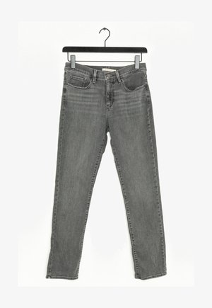 Jeans ajustados de color gris con bolsillos frontales y trabillas para cinturón colgados de una percha negra sobre un fondo blanco.